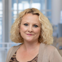 Portr&auml;t einer l&auml;chelnden Frau mit blond-lockigen Haaren vor hellem Hintergrund